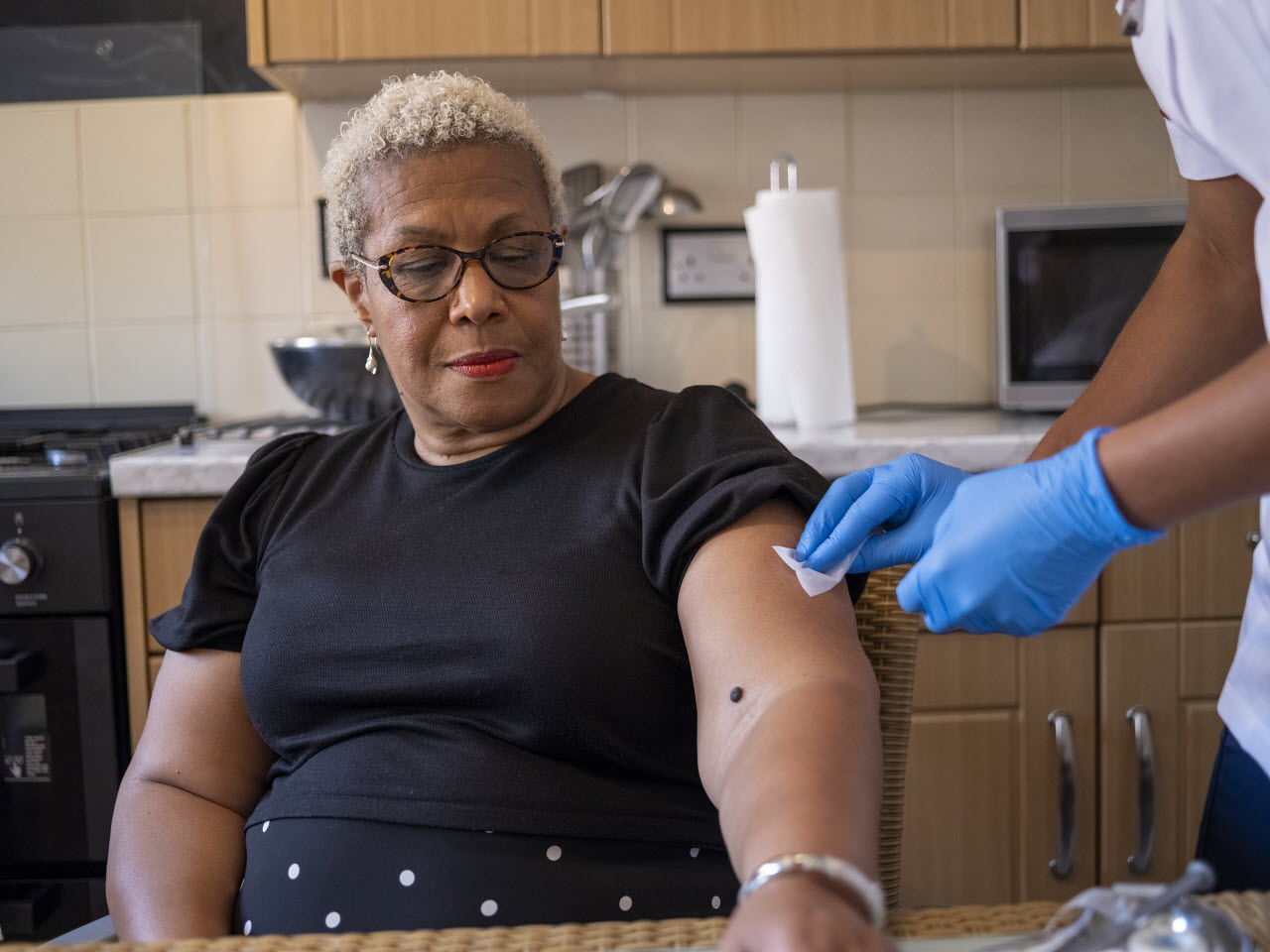 Nurse visiting mature woman in hospice, preparing injection