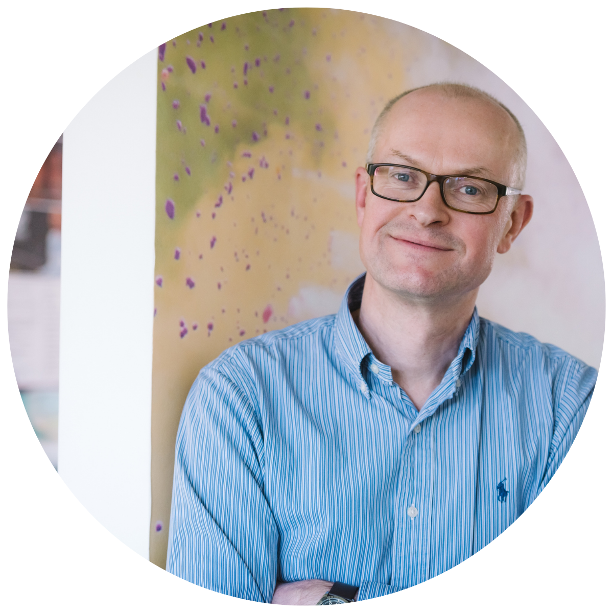 Photo of Matthew Riley, a white man wearing a button up shirt, glasses and smiling