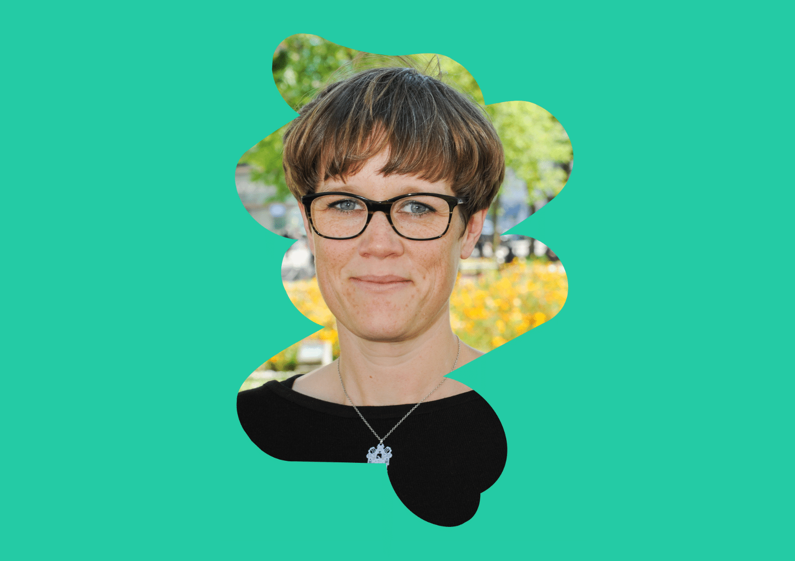 A woman with short brown hair and black glasses is smiling slightly at the camera. She is wearing a black top and a silver necklace. Her portrait is cut out in an abstract organic shape against a bright teal background, with blurred greenery and flowers visible behind her.